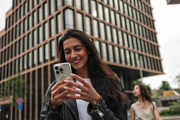 istock Young woman using her smartphone while walking in the city 2220812715