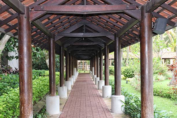 istock Rustic Walkway Surrounded by Greenery Under a Wooden Roof Structure 2220817636