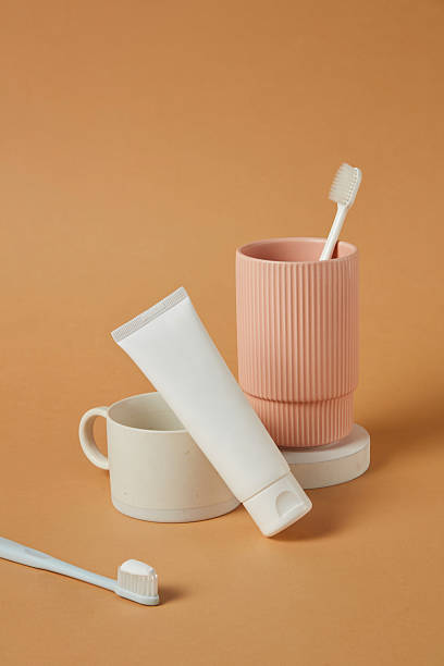 istock Muted coral cup holding oral care items, placed in a centered vertical frame. The scene is sparse, symmetrical, and bathed in soft light, enhancing the minimalist while maintaining product clarity. 2220824996