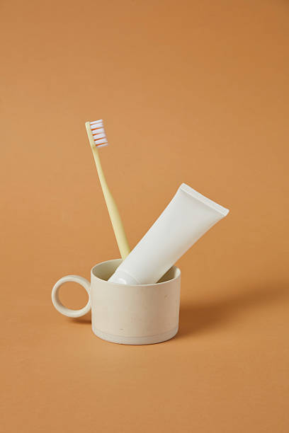 istock Single ceramic cup holding a toothbrush and toothpaste on a brown background. The use of vertical space and earthy tones reflect a minimal and calm lifestyleideal for wellness and bathroom themes. 2220825011
