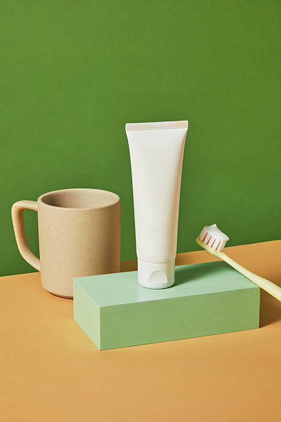istock Toothbrush leaning inside a pastel mug next to a toothpaste tube on a flat green surface. Styled in modern minimalist setup for clean, daily dental routine. 2220825022