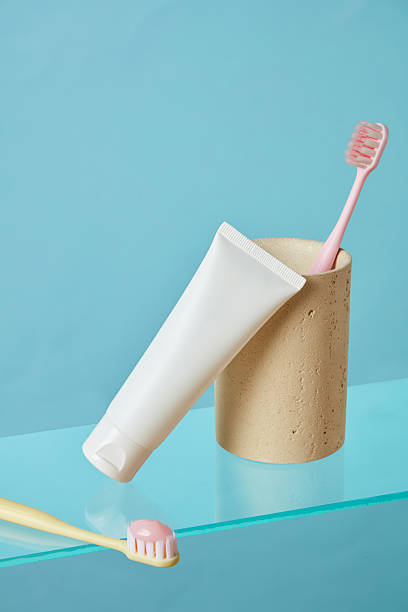 istock Toothbrush and toothpaste tube aligned vertically on green floor with yellow backdrop. Modern minimalist layout with bright pastel harmony for product showcasing. 2220825028