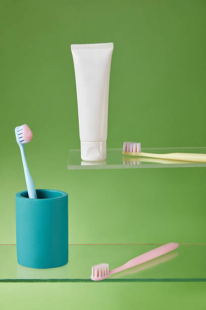 istock Toothbrush placed diagonally with toothpaste tube on pastel yellow-green split background, captured in minimal composition for dental health promotions. 2220825040