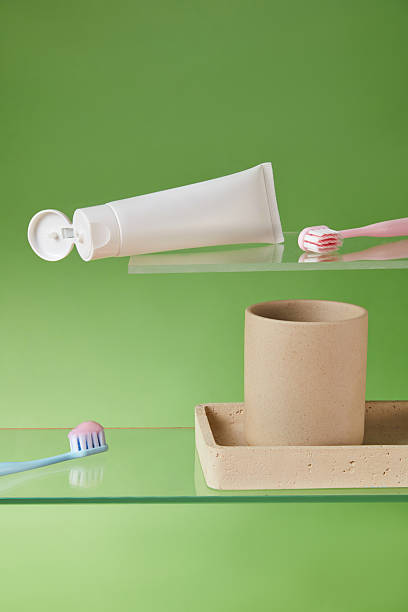Toothpaste tube placed vertically next to a toothbrush on pastel green background with yellow block, styled with clean minimalist tone for wellness-themed visuals.