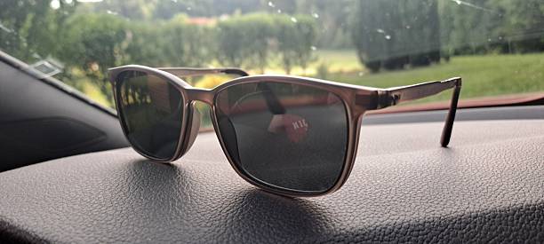 istock Sunglasses on a dashboard of the car,  front window, green outside 2220827286
