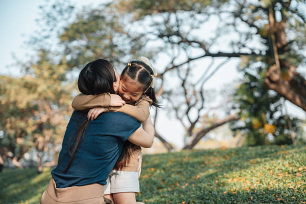 istock Asian mom hugging her little daughter while sitting in the park, taking a break from their playful exploration of the outdoors 2220830563