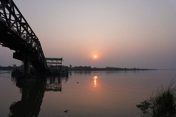 istock A serene sunset scene featuring a bridge spanning a river with the sun low on the horizon and its reflection visible in the water 2220836610