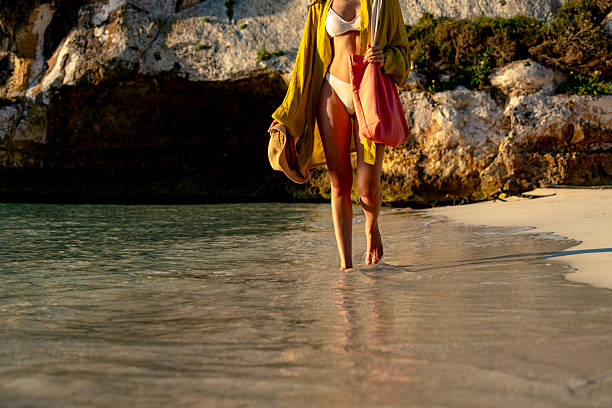 istock Young woman walking on the beach at sunset 2220838632