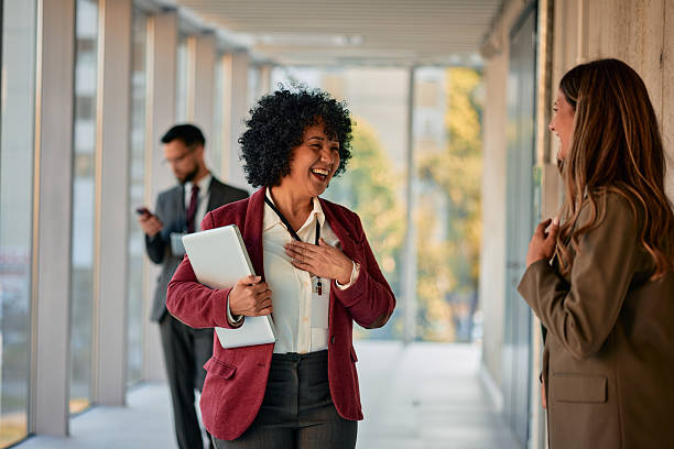 istock Two businesswomen laughing and talking in a modern office hallway 2220840016