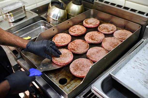 istock Professional cook preparing hamburgers in a commercial kitchen using a metal spatula 2220840026