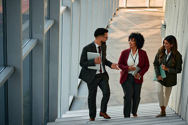 istock Businesspeople walking and talking on stairs in modern office building 2220840134
