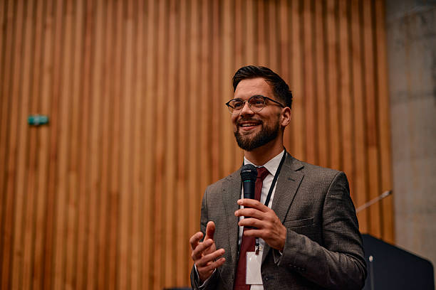 istock Young businessman smiling and speaking at a conference 2220840644