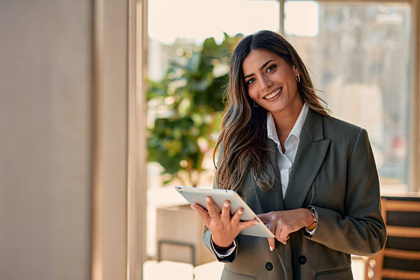 istock Businesswoman smiling and using digital tablet in modern office 2220840885