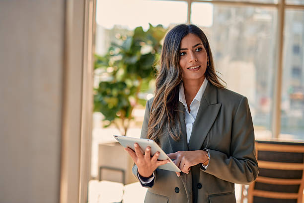 istock Businesswoman using digital tablet in modern office building looking away 2220840900