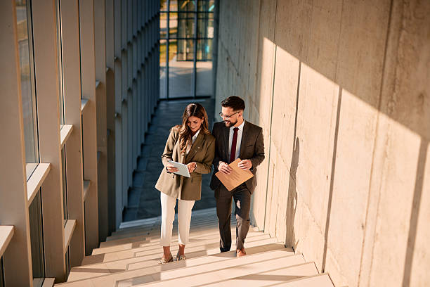 istock Business partners walking down the stairs and discussing a project using a digital tablet 2220841569