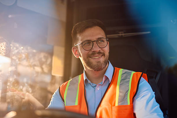 istock Truck driver smiling and driving during sunset 2220843232