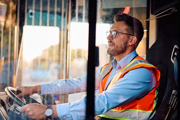 istock Bus driver wearing safety vest driving bus at sunset 2220843334
