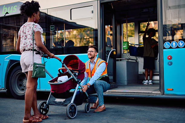 istock Bus driver helping mother with baby stroller to enter the bus 2220843420