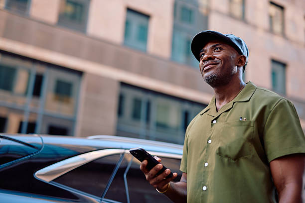 istock Stylish mature man looking up while using smartphone in city 2220844166