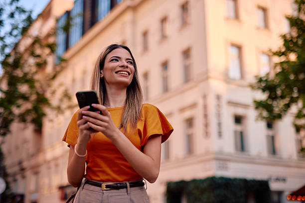 istock Young woman using smartphone and smiling while walking in the city 2220844196