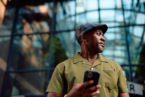istock Stylish mature man using a smartphone in front of a modern glass building 2220844352