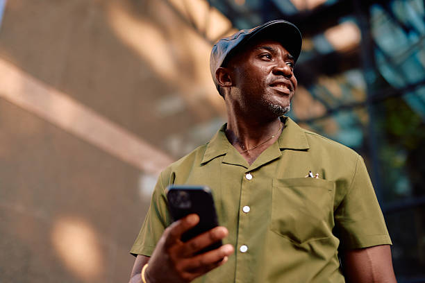 istock Stylish mature african american man using smartphone and looking away 2220844355