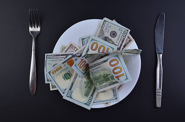 Crumpled dollar bills served on a plate.  A conceptual image of the cost of living, financial struggles, or eating money.