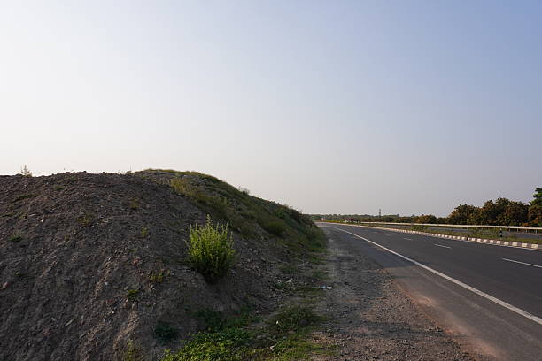 A small, unpaved hill beside the road under the blue sky