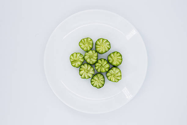 Cucumber, Decorative Cucumber Garnish, Top view of intricately carved cucumber pieces arranged on a clean white plate. Ideal for food styling, healthy eating, and culinary decoration, Vegetable