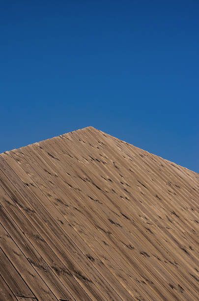 Wooden pyramid roof or structure against a clear, vibrant blue sky. High quality photo