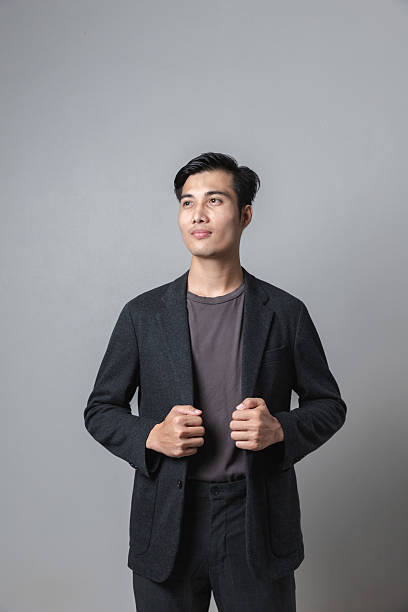 Handsome businessman in Southeast Asia looking up on gray studio background