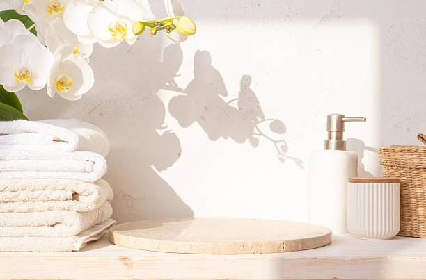 istock Round stone podium with empty space, set of spa bathing tools and orchid flowers on abstract texture plaster wall background in sunlight shadows 2220853106