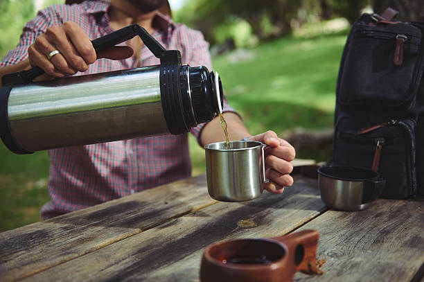 istock Pouring Warm Beverage From Thermos Outdoors on Wooden Picnic Table 2220856932