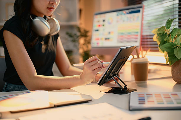 istock Female graphic designer using a digital tablet at a modern desk with color swatches 2220864719
