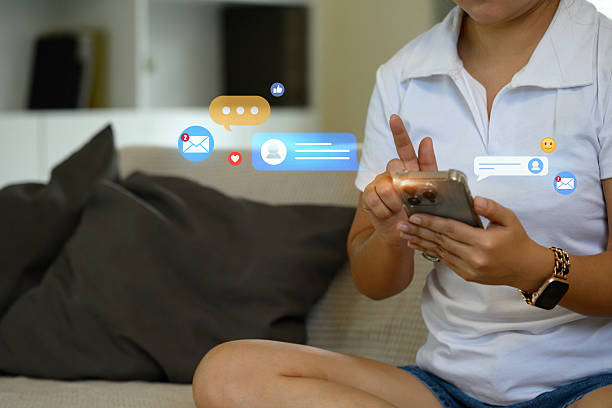 istock Person using smartphone with floating social media icons and notifications 2220865064