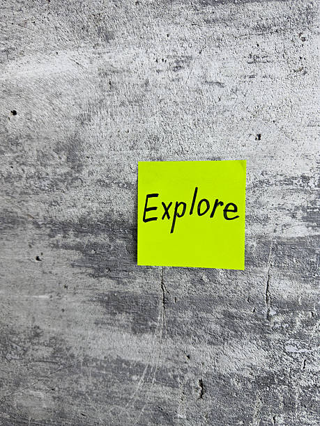 istock Bright yellow sticky note with the word Explore prominently displayed on a textured grey background, signifying the spirit of adventure and the pursuit of new experiences 2220867887