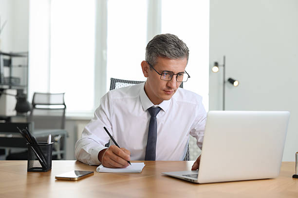 istock Middle aged man working with laptop at table in office 2220871674
