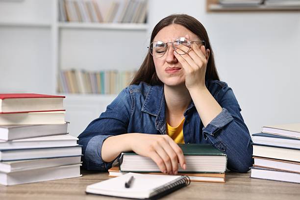 istock Overwhelmed student before exam at table among books indoors 2220872556