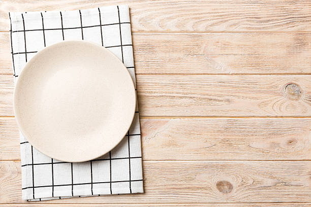 istock Top view on colored background empty round white plate on tablecloth for food. Empty dish on napkin with space for your design 2220873282