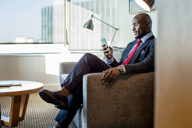 istock Businessman using a smart phone while sitting on a sofa in his Hotel room 2220873330