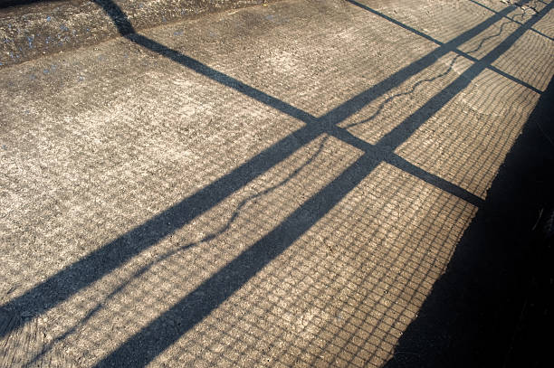 Purple floor covering made of recycled materials. Special rubber coating for children's playground or sports with long shadows of the fence. Protective floor covering with rubber granules.
