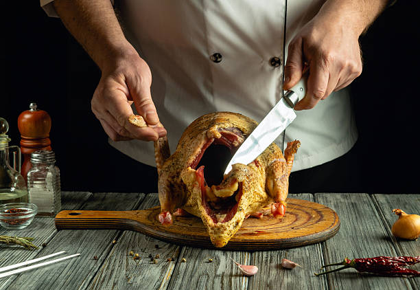 istock A skilled chef carves a raw duck carcass that rests on a rustic wooden board. Fresh ingredients and spices surround the scene, hinting at the passion for culinary art in a cozy kitchen 2220880717
