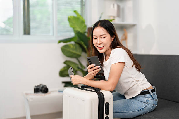 istock Travel excitement. Woman smiling while using smartphone for trip preparations. 2220881169