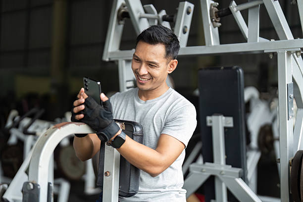 istock Joyful Workout. Man smiling at smartphone while resting at gym. 2220883017