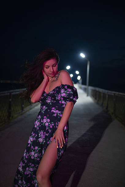 istock Woman in red light posing at night pier 2220884101