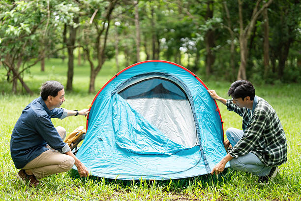 A father and son collaborate to set up their camping tent, showcasing teamwork and family bonding in nature.