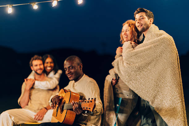 istock Friends singing and playing guitar at night under string lights 2220886173