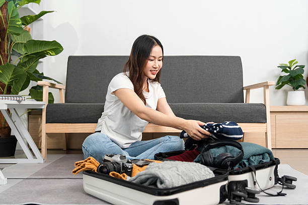 istock Packing for Adventure. Woman smiling while organizing her suitcase. 2220887333