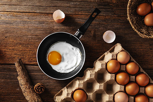 istock Fresh Egg in Frying Pan on Rustic Wooden Table with Eggs Nearby 2220887605