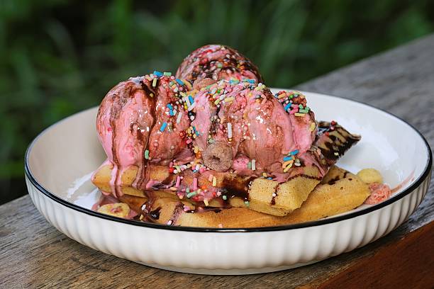 Delicious waffle dessert topped with strawberry ice cream, chocolate drizzle, and sprinkles, perfect for sweet treat lovers